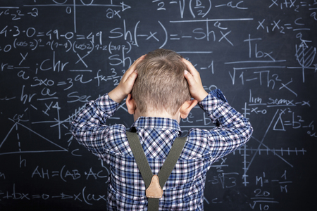 Frustrated boy next to chalk board.